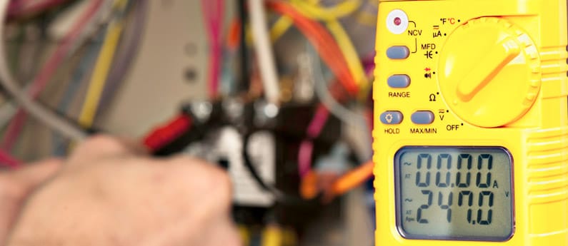 An HVAC technician's device measures various readings while they work on the device in the background.