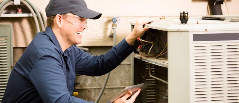 An HVAC worker repairs an air conditioning unit.