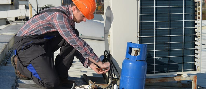 An HVAC technician works on an air conditioning unit